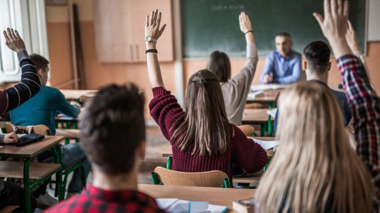 Emigração/Ensino. Sindicato acusa Governo de “modificações de cosmética” que não ajudam ensino de português aos filhos de emigrantes 11 Back view of group of students in the classroom raising hands to answer teacher's question.